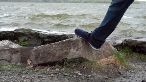 person standing on a rock by the lake