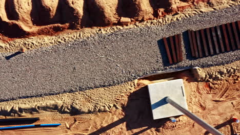 Aerial view of gravel-covered railway construction with steel beams and trenchwork