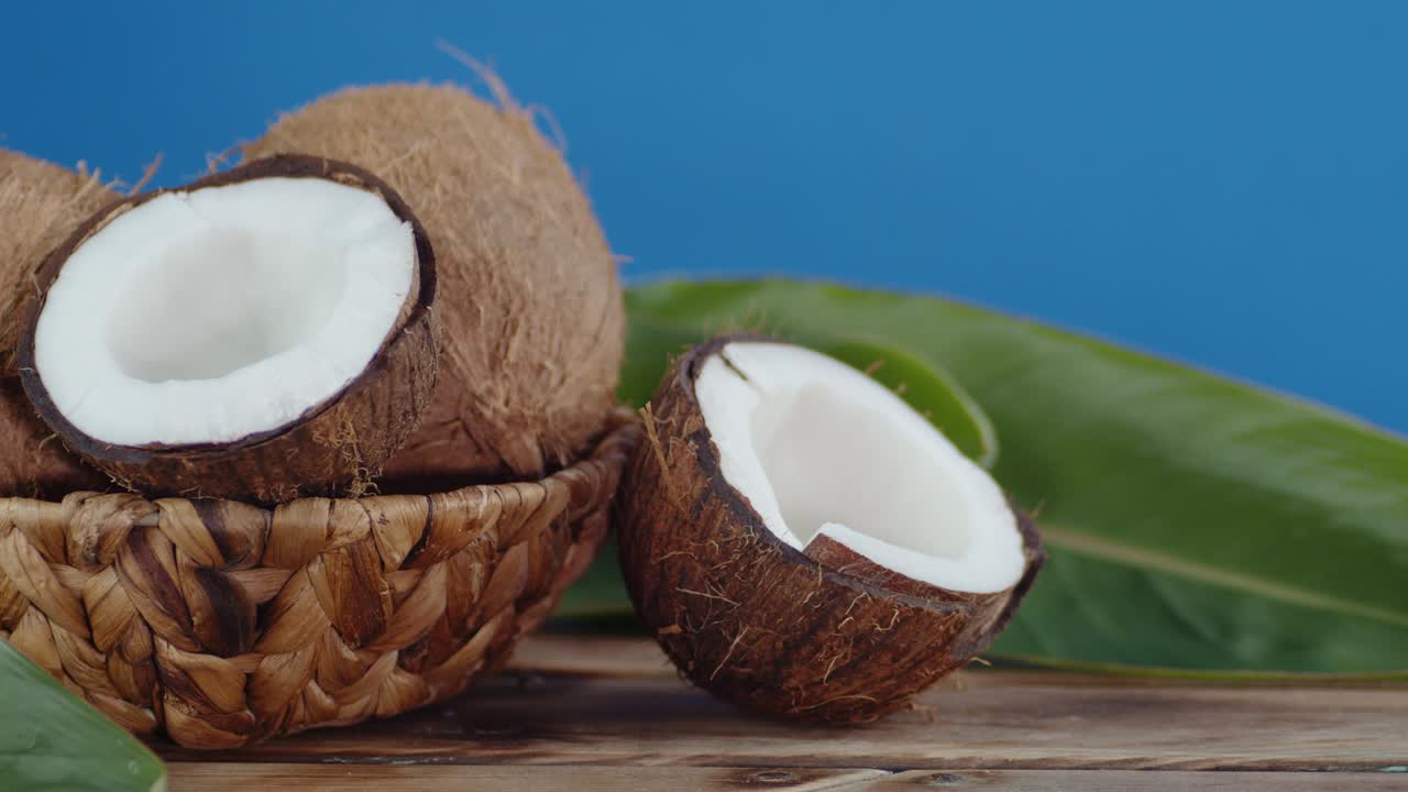 cocos en una canasta en una mesa de madera con follaje.