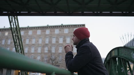 man leans on bridge rail with wuppertal suspended train passing overhead