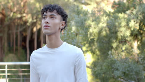 smiling young man in white shirt standing outdoors, enjoying nature, copy space