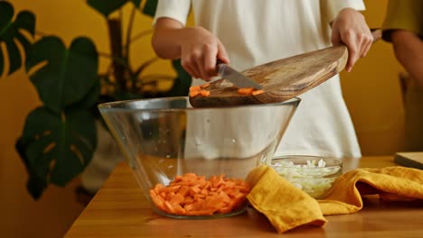 Crop-teenager-putting-carrot-into-bowl