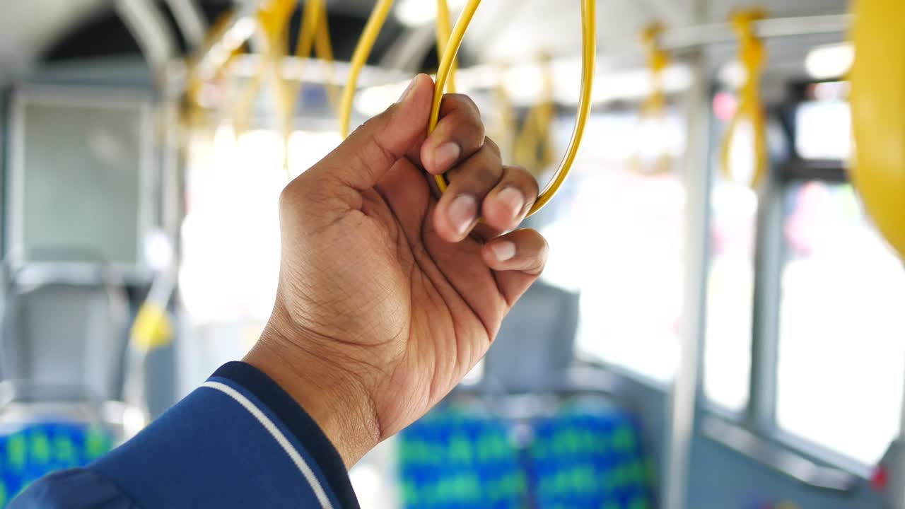 persona que sostiene el mango del autobús