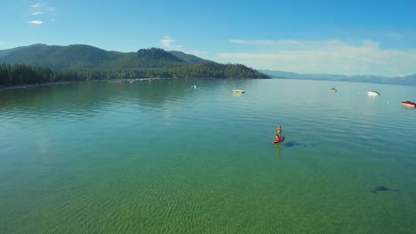 an aerial shot of a woman and her dog paddle boarding on lake tahoe