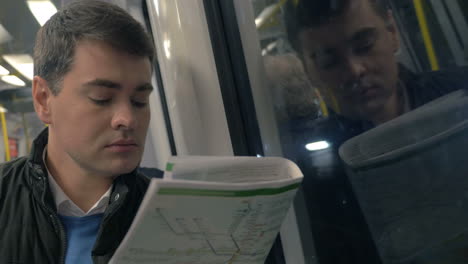 hombre con periódico viajando en el tren del metro