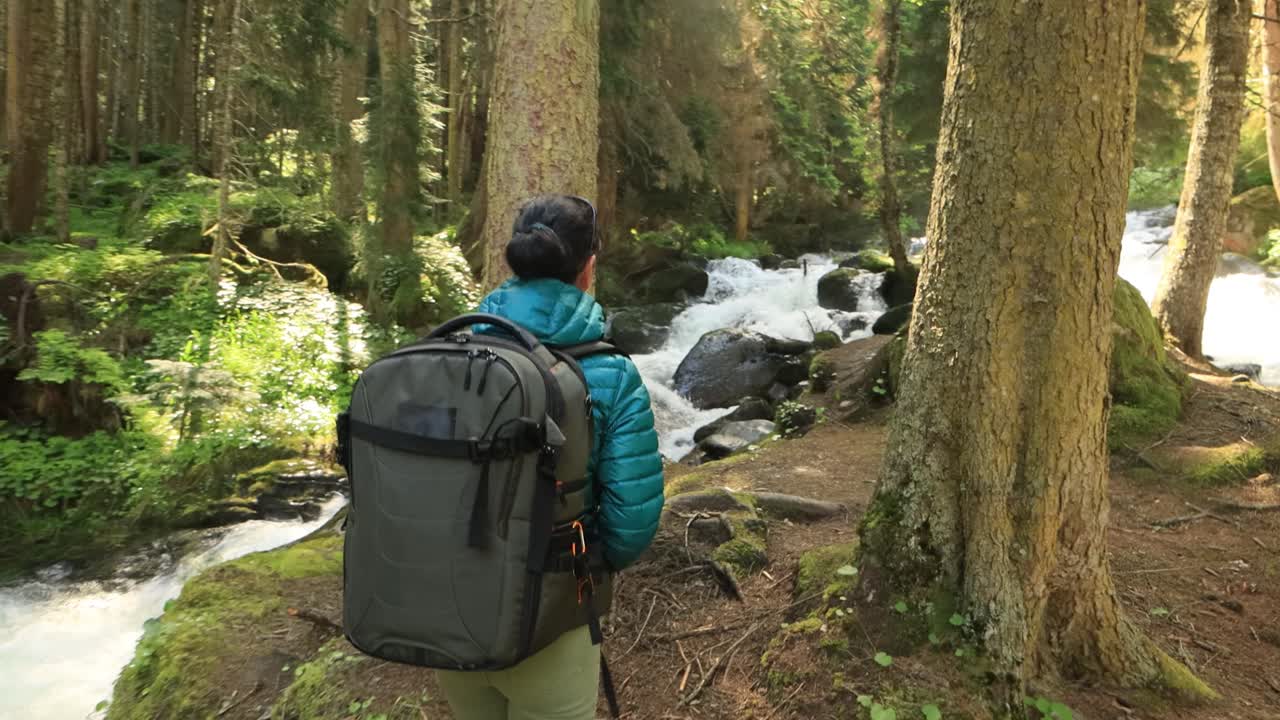 mujer caminando con una mochila de senderismo en el bosque verde de primavera