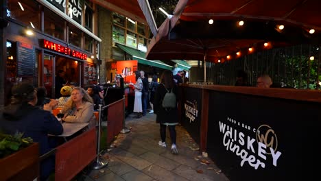 woman walks through borough market in london, surrounded by people and outdoor dining spots