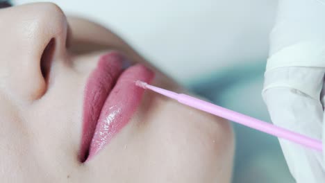 the cosmetologist applies local anesthesia to the clients lips. permanent makeup procedure
