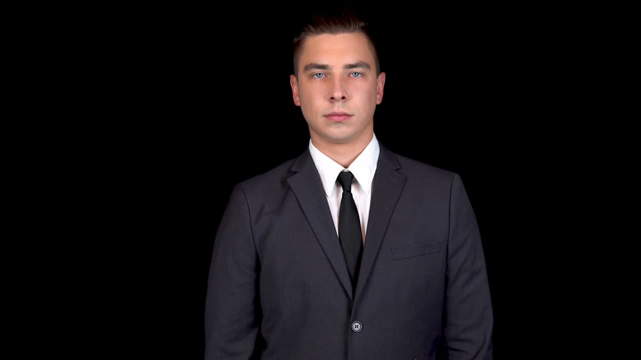 Young businessman shows biceps in his arms. Man in a black suit on a black background