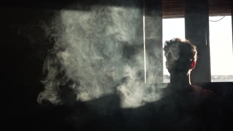 silhouette of a man vaping in the dark in slow motion