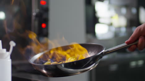 chef flambeing and tossing vegetables in skillet