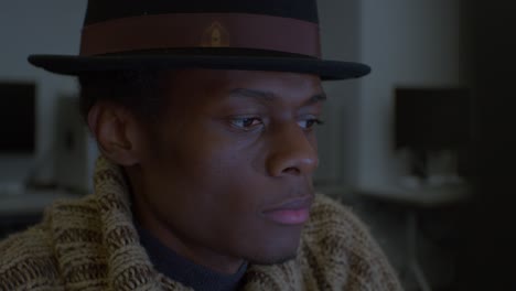 hombre con sombrero fedora negro trabajando en la computadora en el estudio - cerrar
