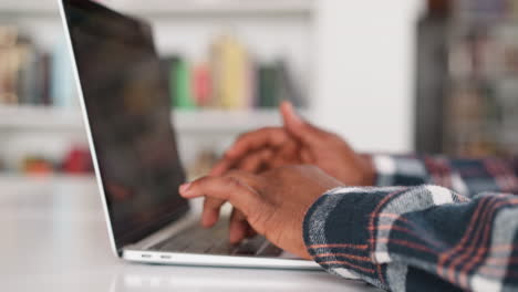 student types on laptop in university library. young black guy uses advanced technologies during creating presentation for class. modern skills