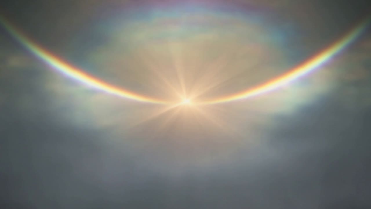 Sol que se ilumina produciendo un arcoíris intenso a través de un velo de nubes delgado y rayos estelares