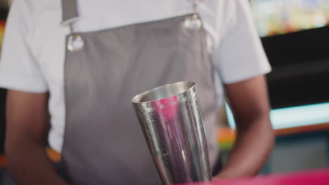 barman puts ice cubes into shaker with scoop closeup. black barkeeper prepares ingredients for cocktail. african american bartender works in nightclub