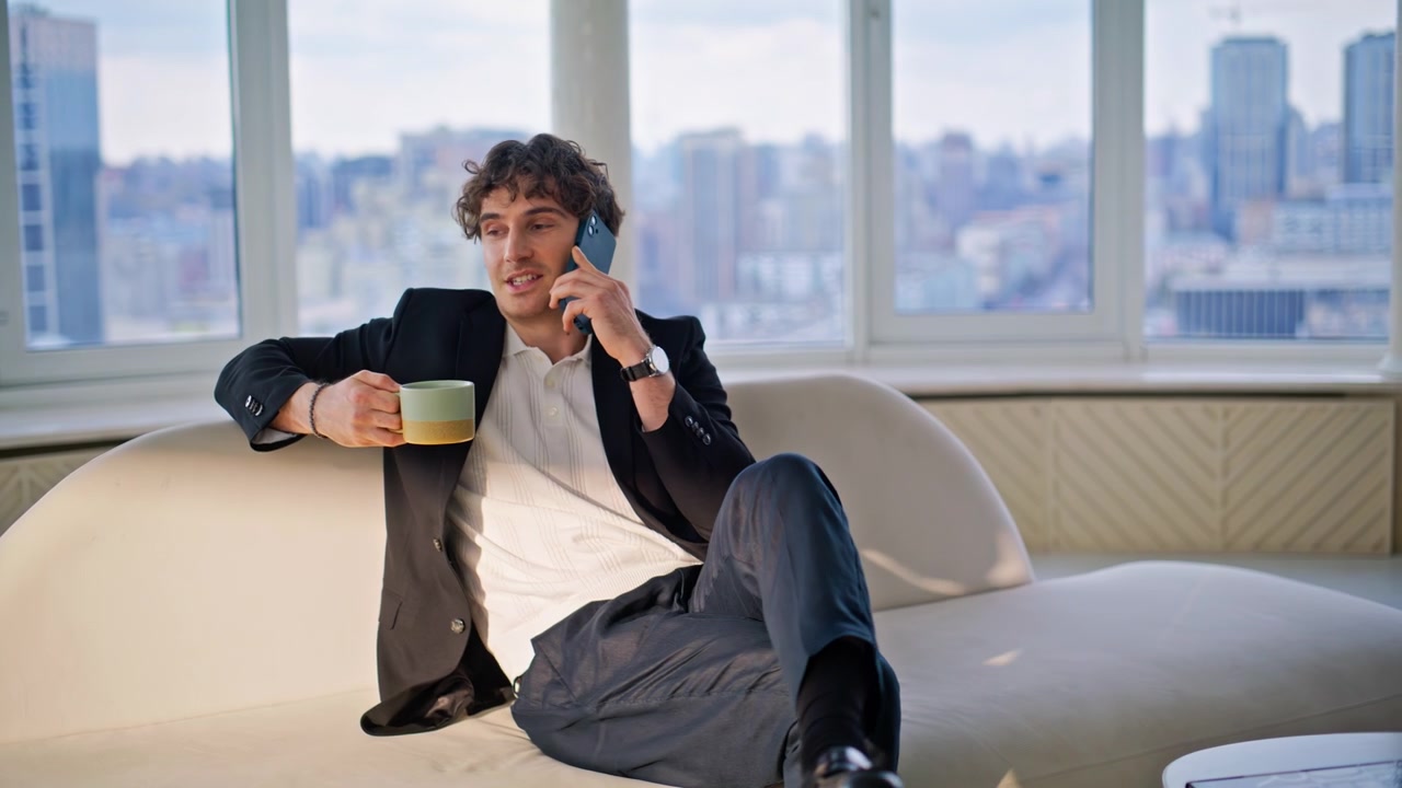 Man talking phone drinking coffee luxury apartment. Businessman relaxing home.