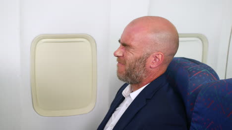 a man suffering with high altitude pressure popping ears with earache on a passenger plane airliner airplane