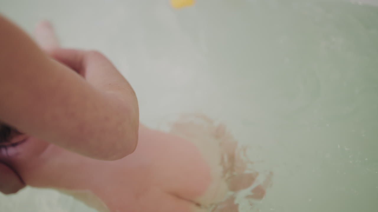 Close up of a baby supported by an adult during bath time
