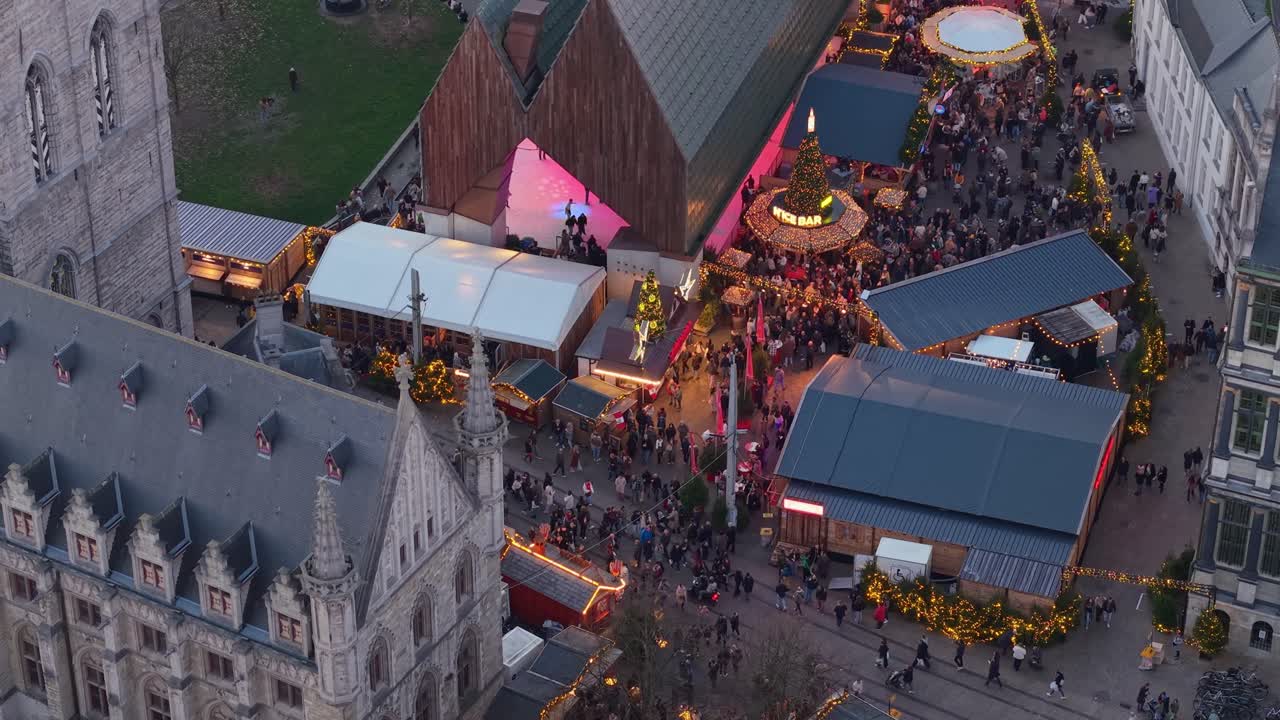 Drönarvy över Gents julmarknad med skridskoåkare framför Het Belfort van Gent, som fångar festliga ljus och julstämning