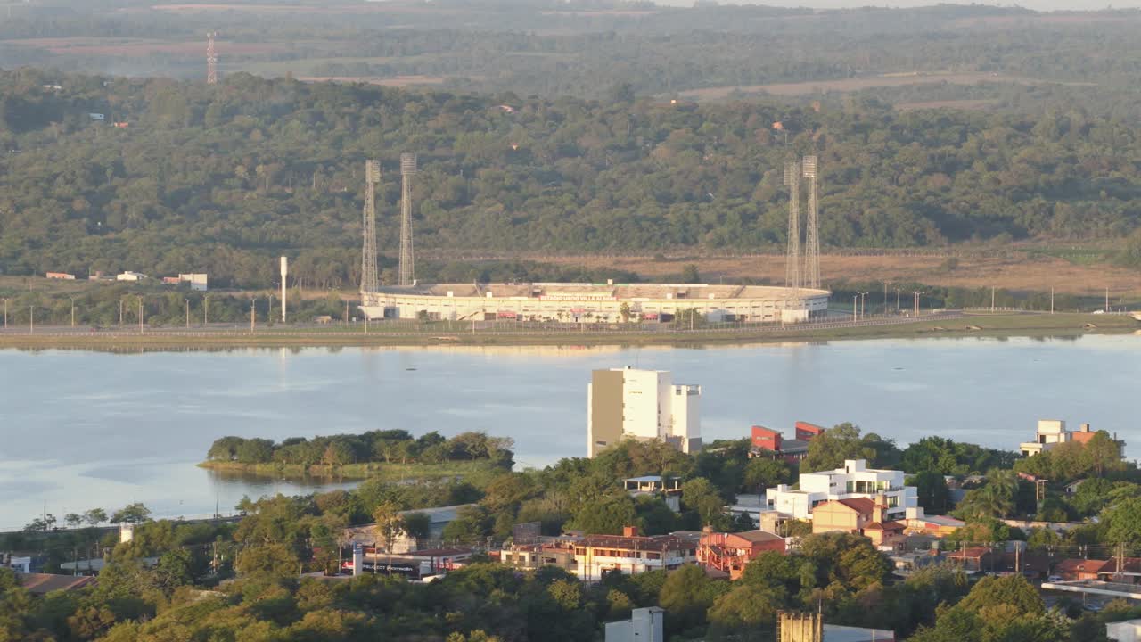 Aerial view of the football stadium in Encarnación, Paraguay, with forest and river views in the background.