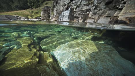 enchanting over-under view of a shallow river with transparent waters and a small waterfal