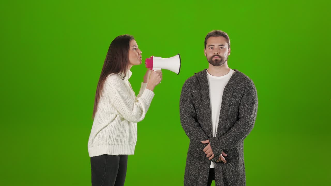 Woman shouting in megaphone while man standing calm