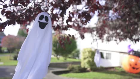 primer plano de seguimiento de la espeluznante decoración fantasma de halloween colgando de un árbol y balanceándose con el viento en un barrio residencial