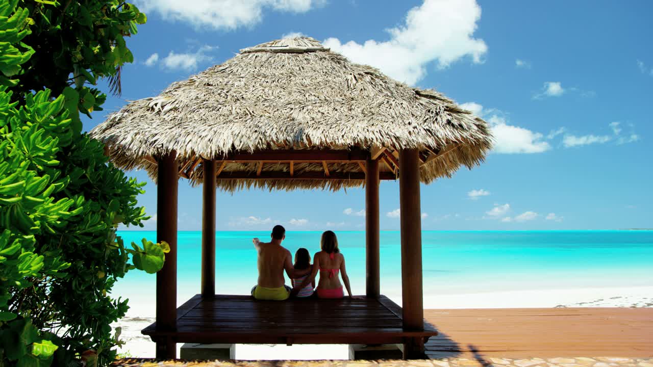 Caucasian family sitting in a tiki beach hut