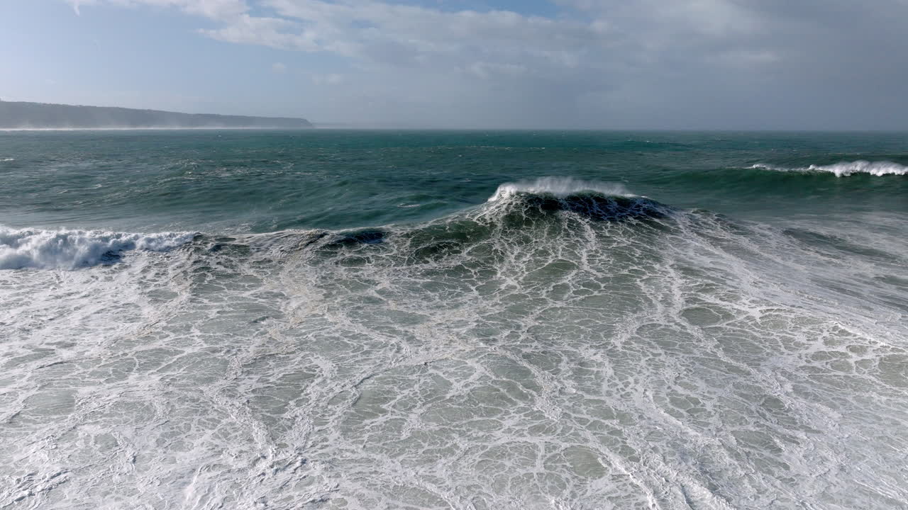 Aerial drone shot of big waves coming into shore on a day with giant waves in Nazaré, Portugal. Surf and white water