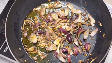 cooking chopped red bell peppers and onions in a pan