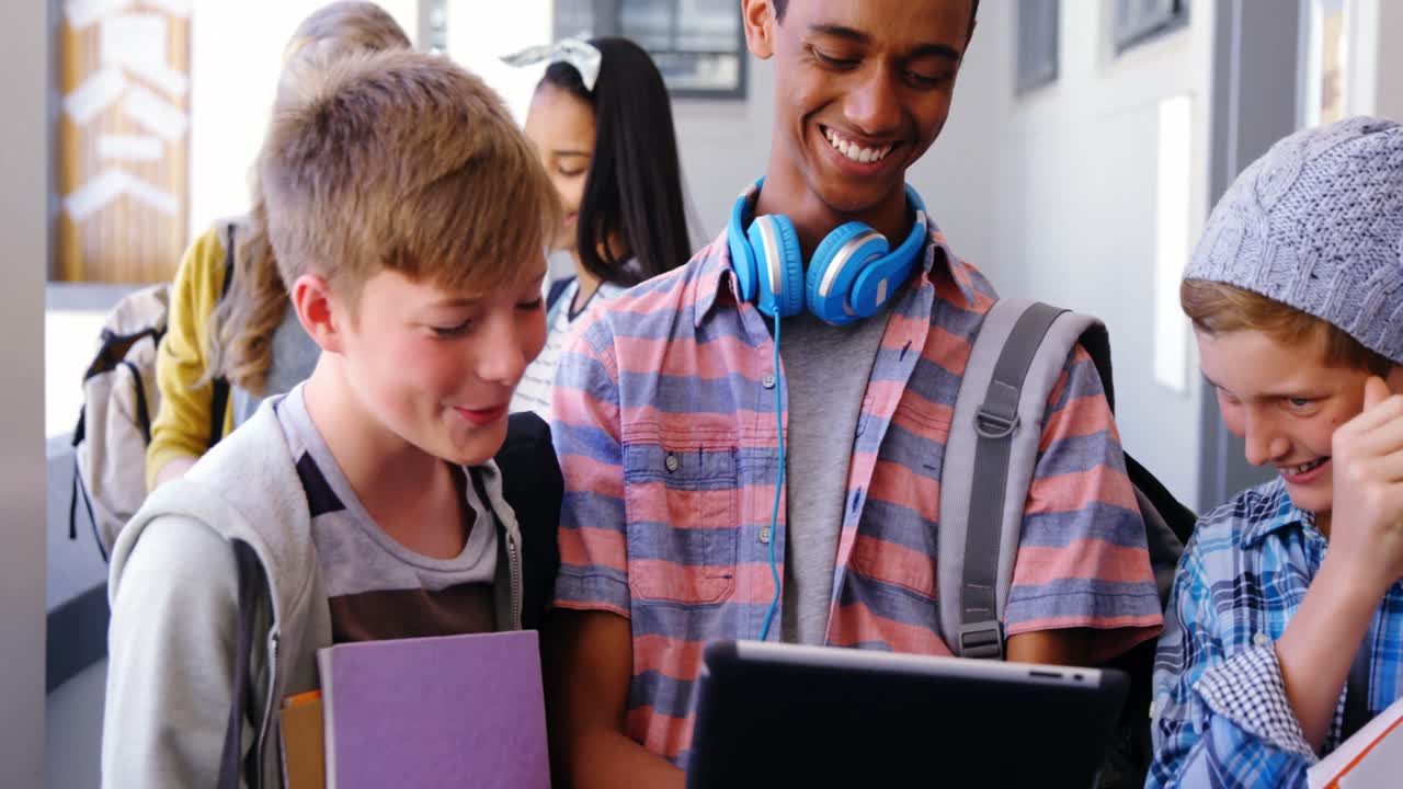 Students standing with notebook and digital tablet in corridor