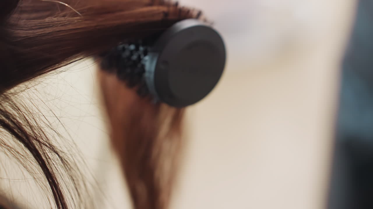 stylist muotoilee laineita, kampaaja luo pehmeitä kiharapohjia, lähikuva ammattitaitoisesta kampaajasta lämmittämässä hiusmuotoiluvälineitä, kauneusalan ammattilainen muotoilee herkkiä laineita lämmitetyillä muotoiluvälineillä