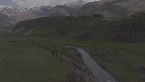 establishing shot of hikers looking down onto a river running between the mountains