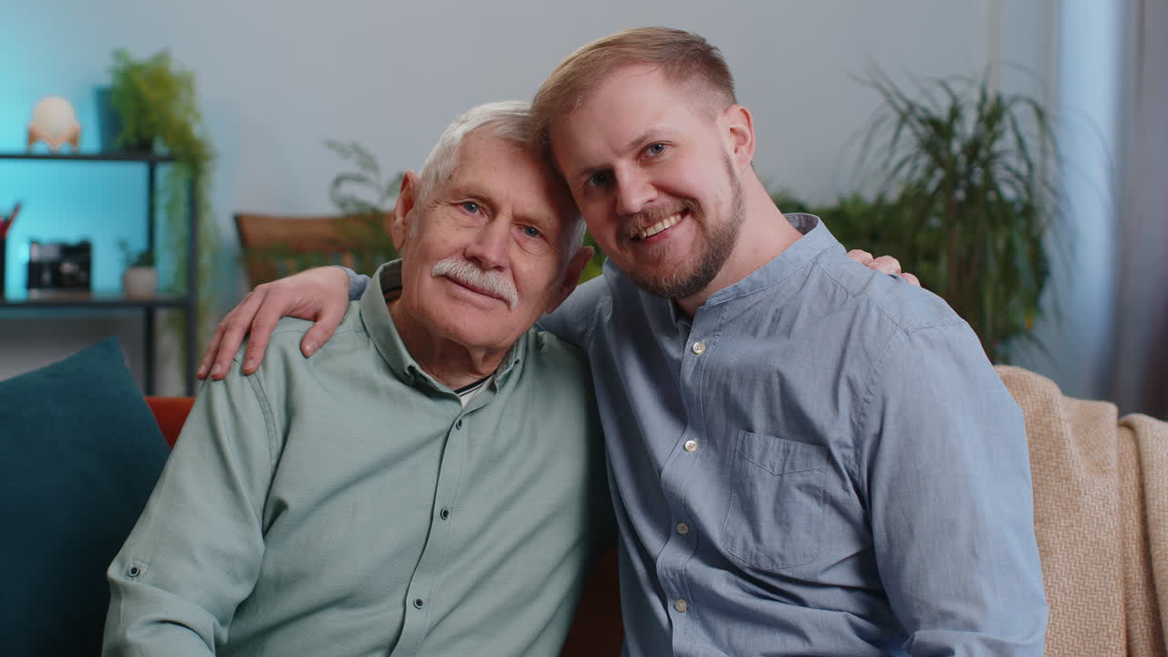 Retrato de avô sênior com neto jovem adulto sorrindo feliz abraçando abraçando em casa