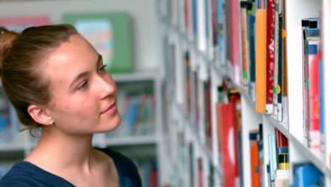 estudiante seleccionando un libro de la estantería de la biblioteca