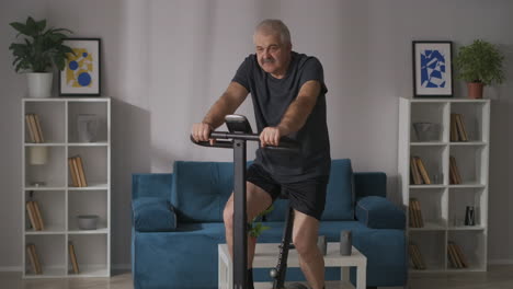 sport and healthy lifestyle at middle and old age man is training on stationary bike at home keeping fit and health of body