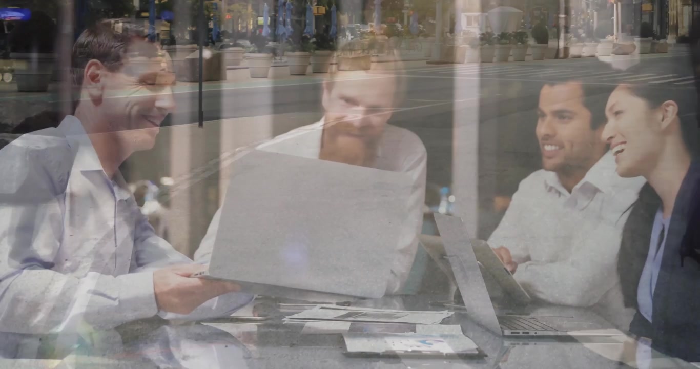 Responsabile del team che fa scorrere un rapporto stampato al team durante una riunione di lavoro in un caffè, analizzando i grafici sul laptop e sorridendo.