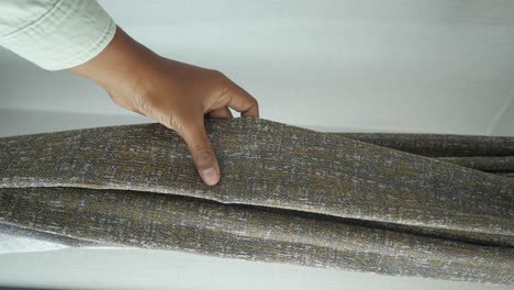 person examining grey and brown fabric sample