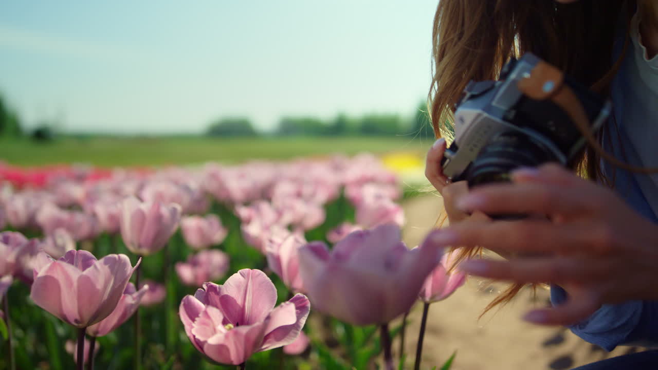 mujer hermosa de primer plano tomando fotos con cámara profesional en el campo de flores.