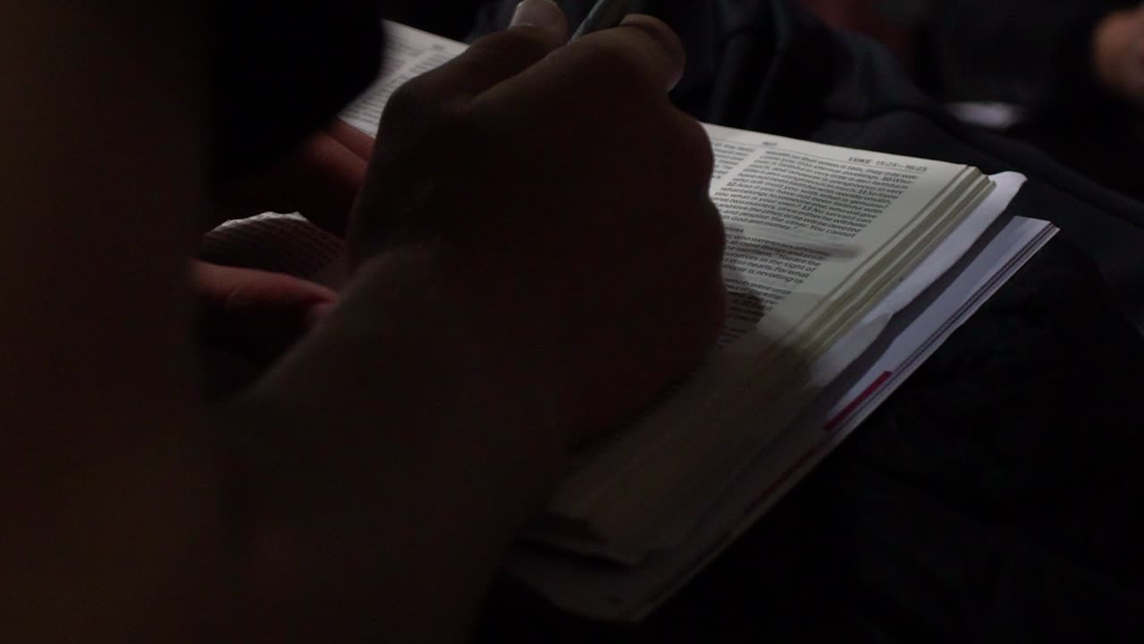 close up shot of someone reading and writing in a bible