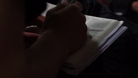 close up shot of someone reading and writing in a bible