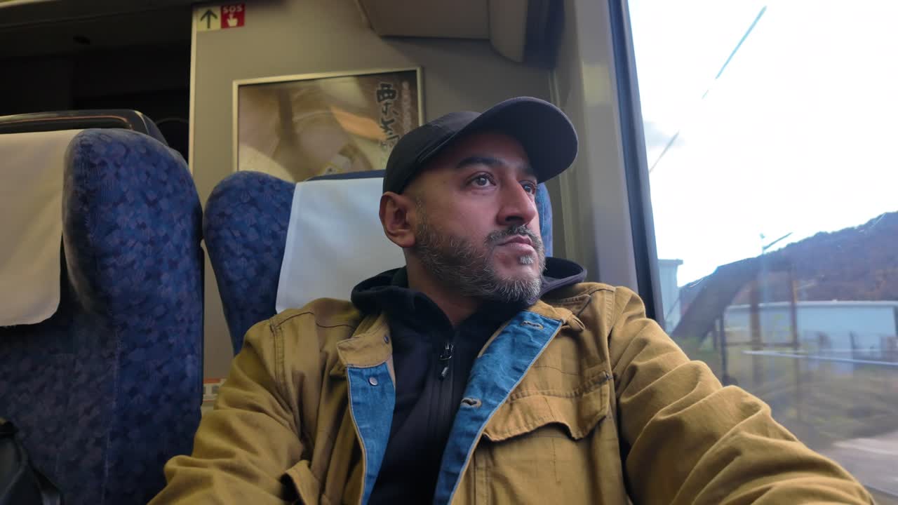 South asian tourist traveling solo by train is looking out the window enjoying the view of the landscape during a sunny day