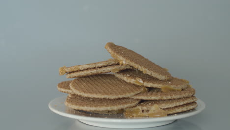 hand grabbing stroopwafel from pile of cookies - wide