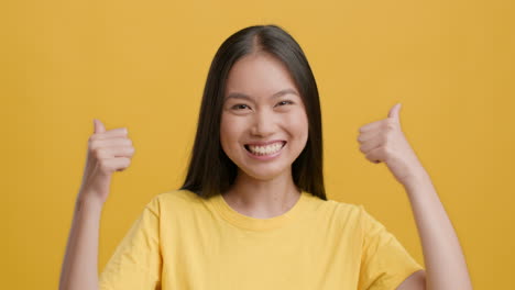 young asian woman giving thumbs up and smiling