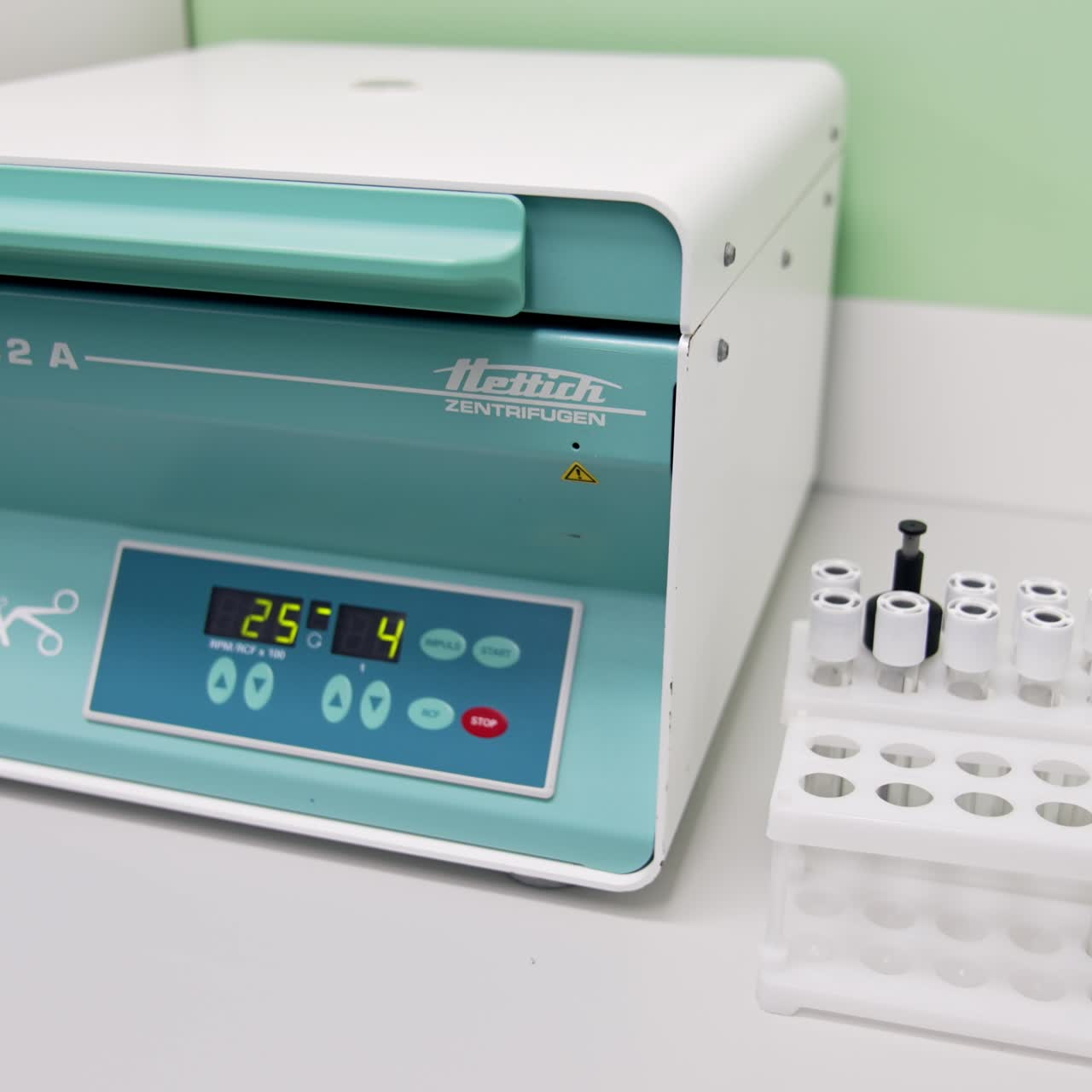 Centrifuge system for getting conditioned plasma. Numbers changing at the indicator panel. Set of test tubes beside the machine. Close up