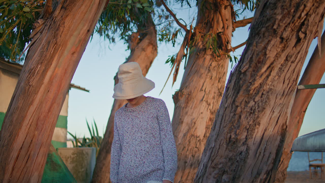 chica sonriente posando árboles en la orilla del lago por la noche. mujer casual descansando al aire libre