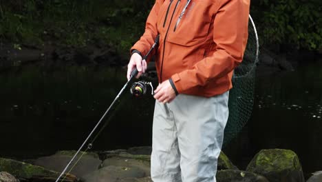 hand-held shot of a fisherman reeling in his lure and attempting to catch a fish