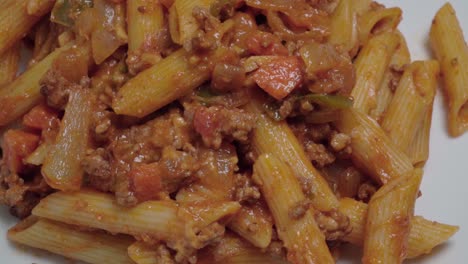 rotating pasta bolognese with penne noodles, overhead closeup