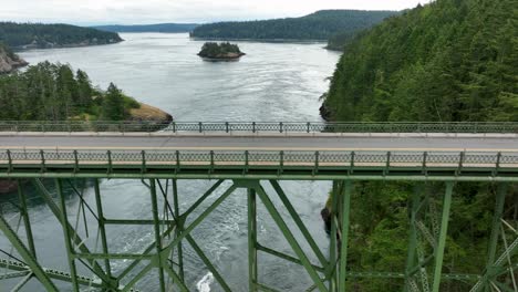 panning aerial shot of a truck driving over the bridge at deception pass