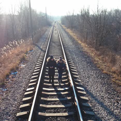 two little boys walking on a railroad. children in warm clothes go on a rail on nature background in winter time.
